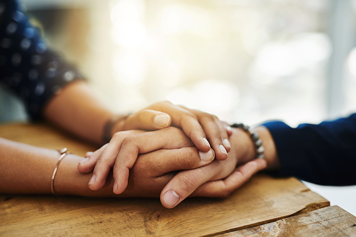 Photo of one person's hands holding another person's hand